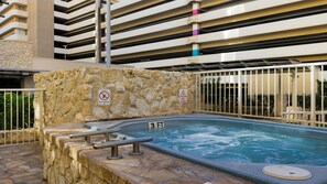 En swimmingpool med stenvæg, metalgelændere og to advarselsskilte, der angiver forbud mod dykning og vådt gulv.
