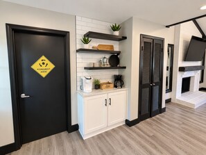 Una cocina moderna con armarios blancos, encimeras negras y una puerta negra con el letrero 'ROUNDABOUT AHEAD'.