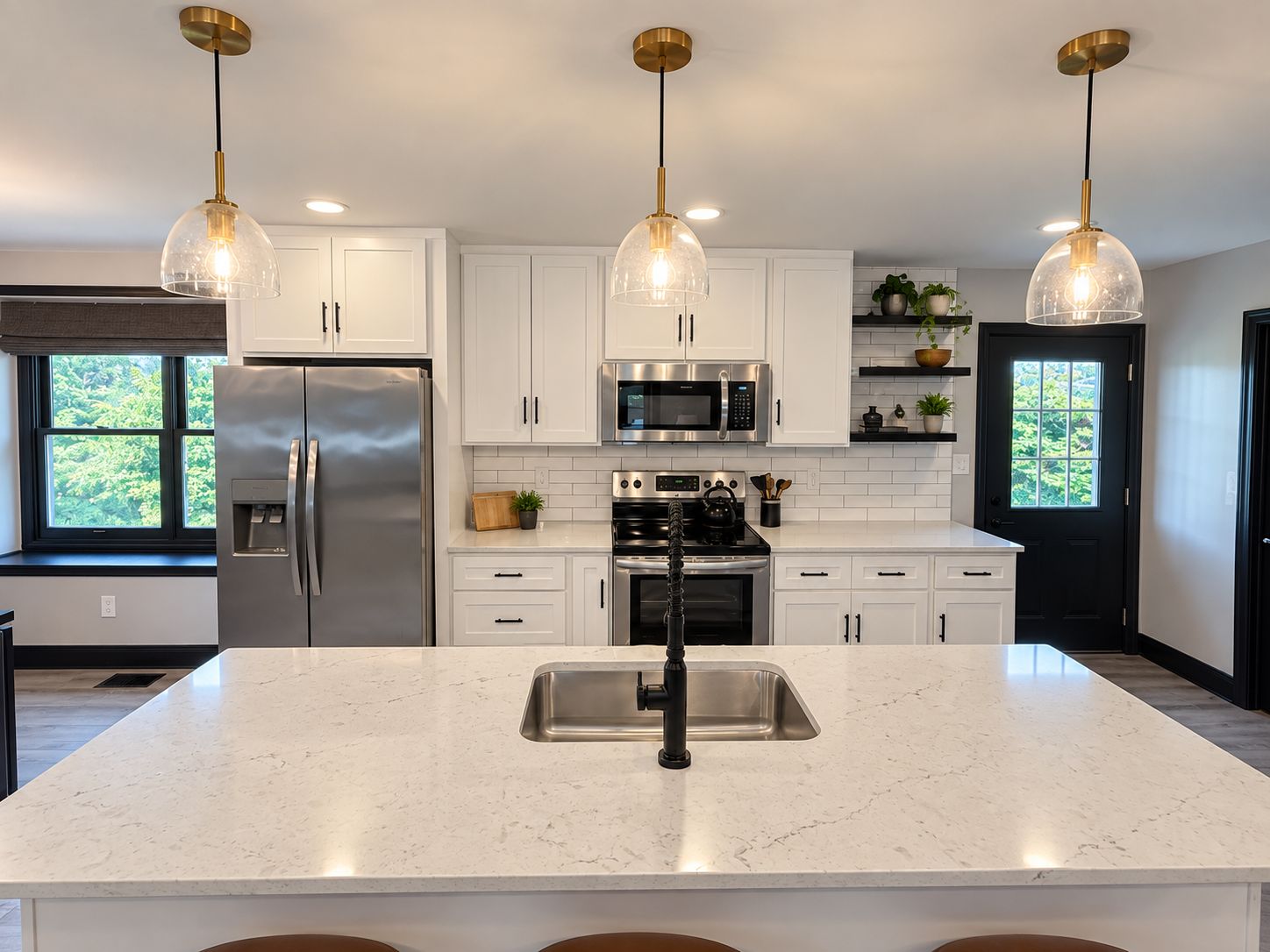 A modern kitchen with white cabinets, stainless steel appliances, a central island with a sink, and pendant lighting.