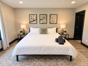 A hotel room with a large bed, two bedside tables with lamps, a fluffy throw pillow, and three framed artworks on the wall. - Charming 3 Bedroom Ranch in Keystone at the Crossing (Indianapolis)