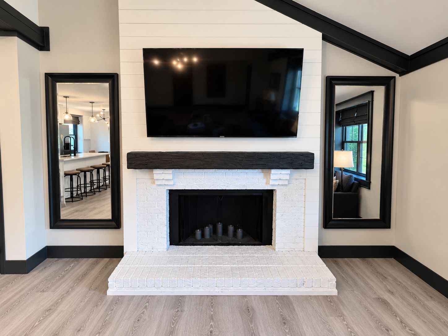 A modern living room with a fireplace, a mounted television, and a kitchen visible through an open door.