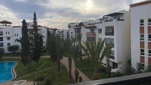 Zona residencial con edificios blancos, piscina y palmeras.
