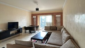 Una sala de estar con un sofá, un televisor, una mesa de centro y un comedor con sillas y una mesa.