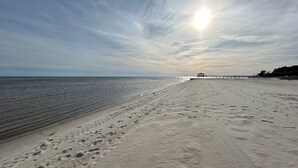Una playa con huellas que conducen a un muelle.