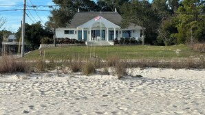 Propiedad frente al mar con una casa que tiene un porche y una bandera estadounidense.