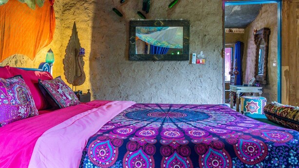 Een kamer met een bed, een spiegel aan de muur en een plank met diverse spullen.