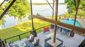 A deck with outdoor seating, a pool, and a view of a lake.