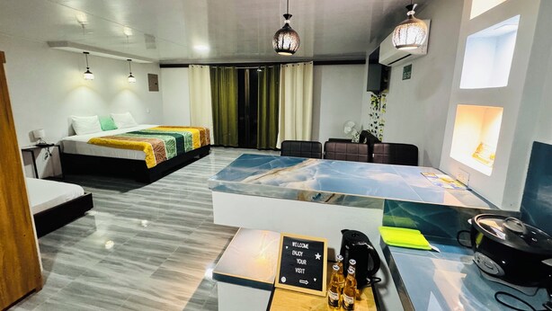 Ein modernes Hotelzimmer mit einem Bett, einem Schreibtisch mit einem Schild, einer Kaffeemaschine und einem Ventilator.
