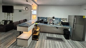 Eine moderne Küche mit Marmorarbeitsplatte, integrierten Geräten und einer Sitzecke mit einer Couch.