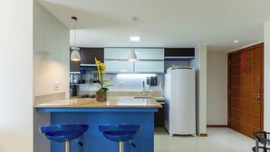 Une cuisine moderne avec des tabourets de bar bleus, un réfrigérateur et un four à micro-ondes.