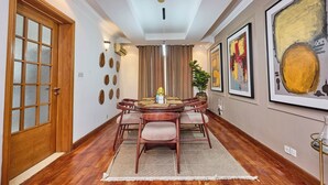 A dining area with a round table, chairs, and a chandelier. - LAGOS RESIDENCES 4BED IKOYI HC (Lagos)