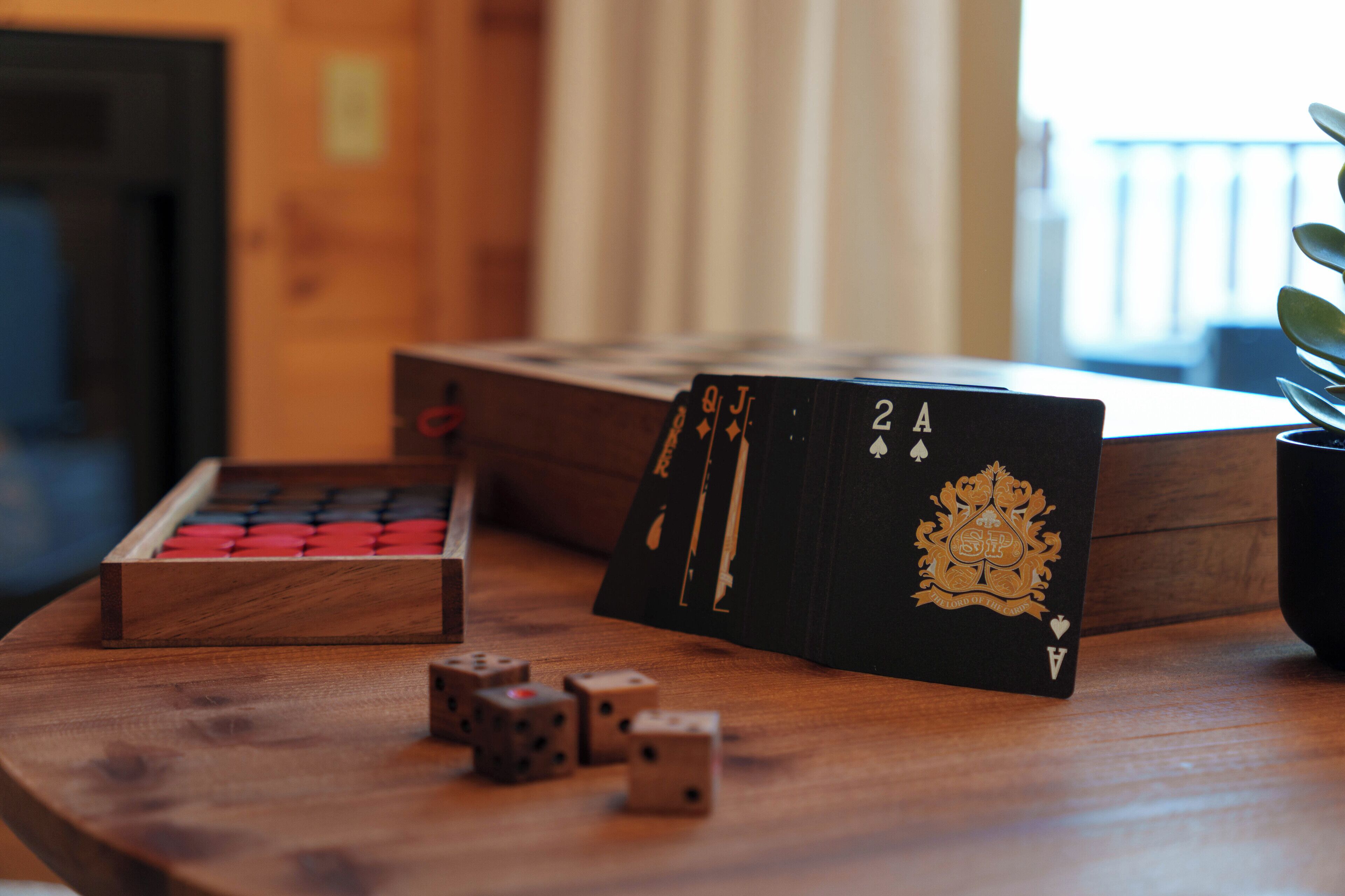 A wooden table with a deck of cards, a set of dice, and a plant.