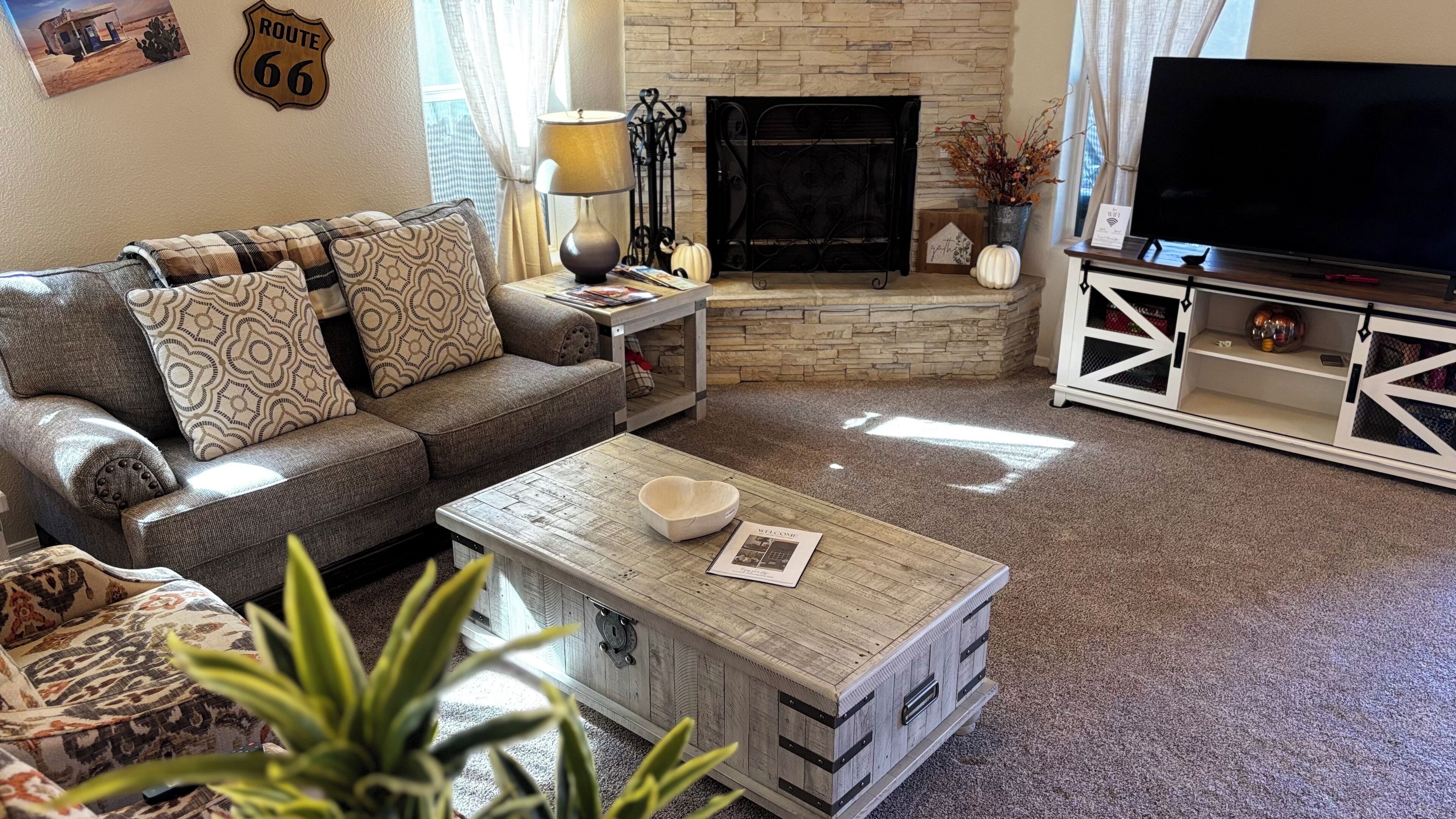 Una sala de estar acogedora con sofá, mesa de centro, chimenea, televisor y objetos decorativos.