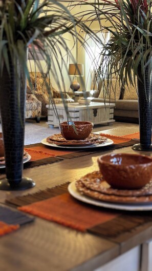 Un comedor con una mesa de madera, dos cuencos decorativos y una planta en maceta.