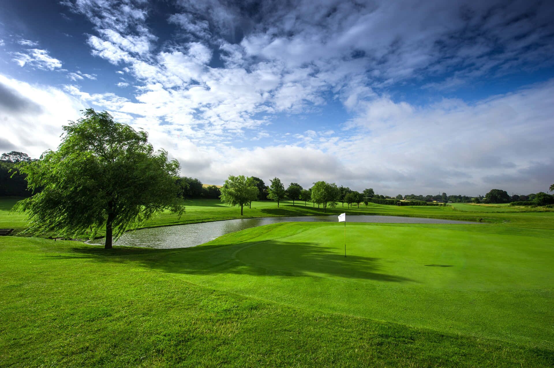Un parcours de golf avec des verts bien entretenus, un étang et un drapeau indiquant le trou.