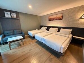 A hotel room with two beds, a sofa, a small table, and a cityscape painting on the wall. - BB House Chaingmai (Chiang Mai)