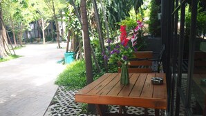 A wooden table with a vase of flowers, benches, and a patterned walkway. - BB House Chaingmai (Chiang Mai)