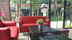 A seating area with red sofas, a black table, and a potted plant. - BB House Chaingmai (Chiang Mai)