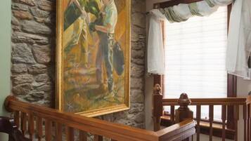 A room with a stone wall, a wooden staircase, and a painting.