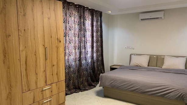 Ein Schlafzimmer mit einem Bett, einem Kleiderschrank, einem Vorhang und einer Klimaanlage.
