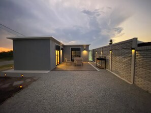 A modern building with a patio area, a covered seating area, and a brick wall.