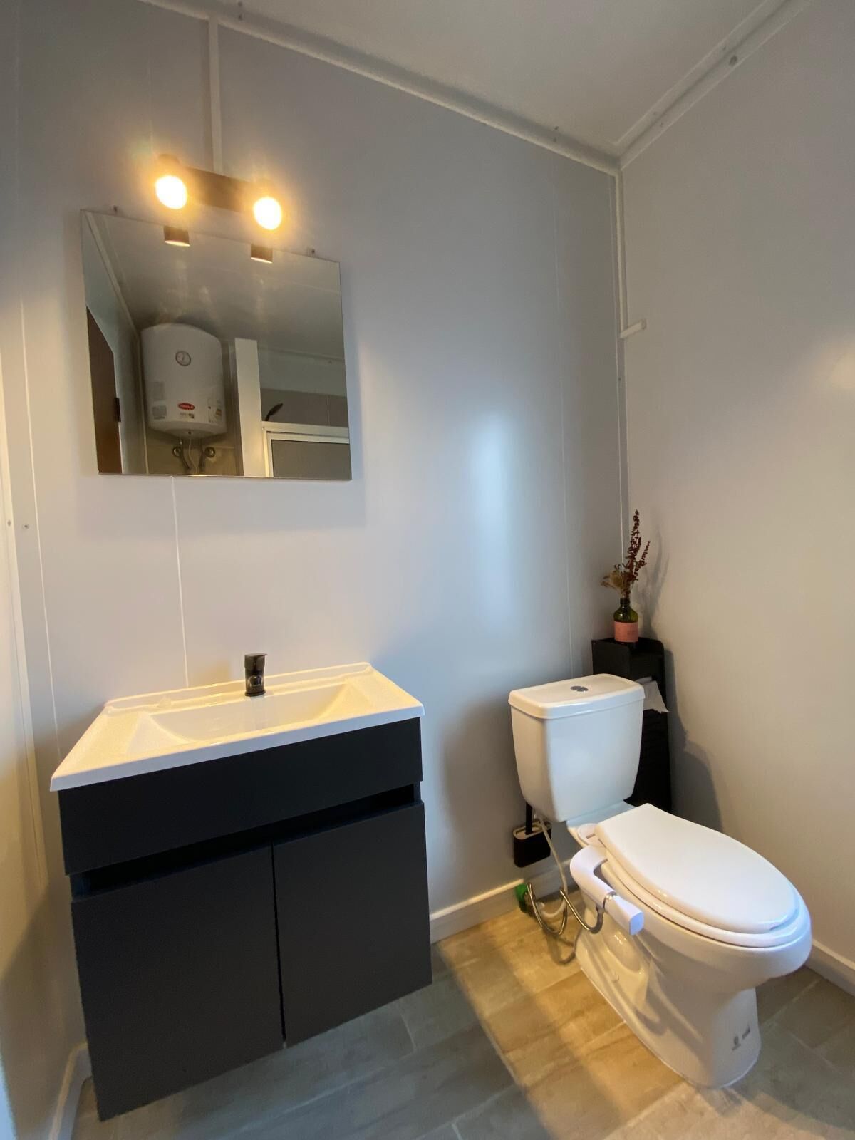 A modern bathroom with a white sink, black vanity, and a toilet.