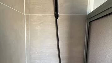 Um chuveiro com um chuveirinho manual e uma mangueira manual.