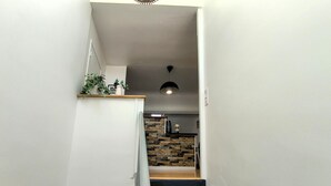 Una escalera que lleva a una cocina con salpicadero de piedra.