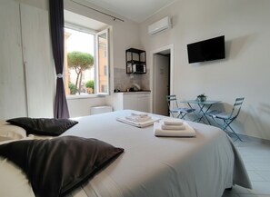 A hotel room with a bed, a desk, a chair, a TV, and a window with curtains. - Pansini Ruggiero's Apartaments (Naples)