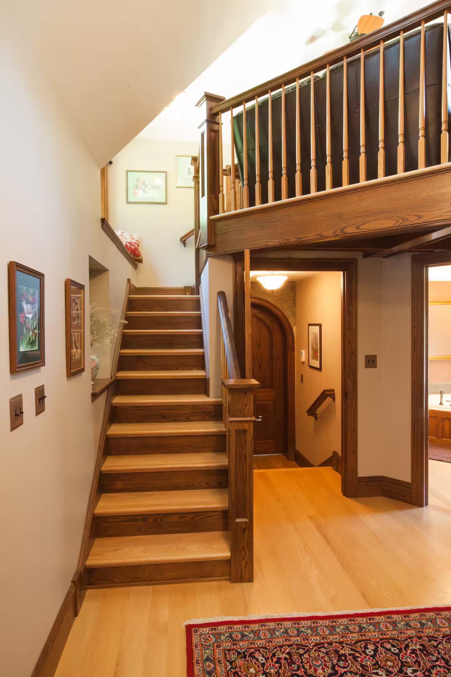 A wooden staircase with a handrail leading to a second-floor landing.