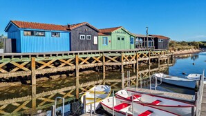 Une jetée en bois bordée de bâtiments aux couleurs vives, une rivière paisible et des bateaux amarrés.