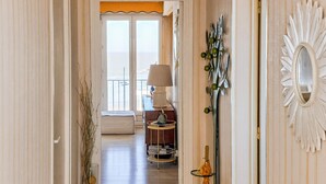 Un couloir menant à un balcon avec vue, une lampe et un miroir décoratif.