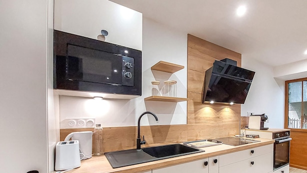 A modern kitchen with a built-in microwave, a black faucet, and wooden cabinetry. - 1 bedroom lovely home in Verteuil-sur-Charente (Verteuil-sur-Charente)