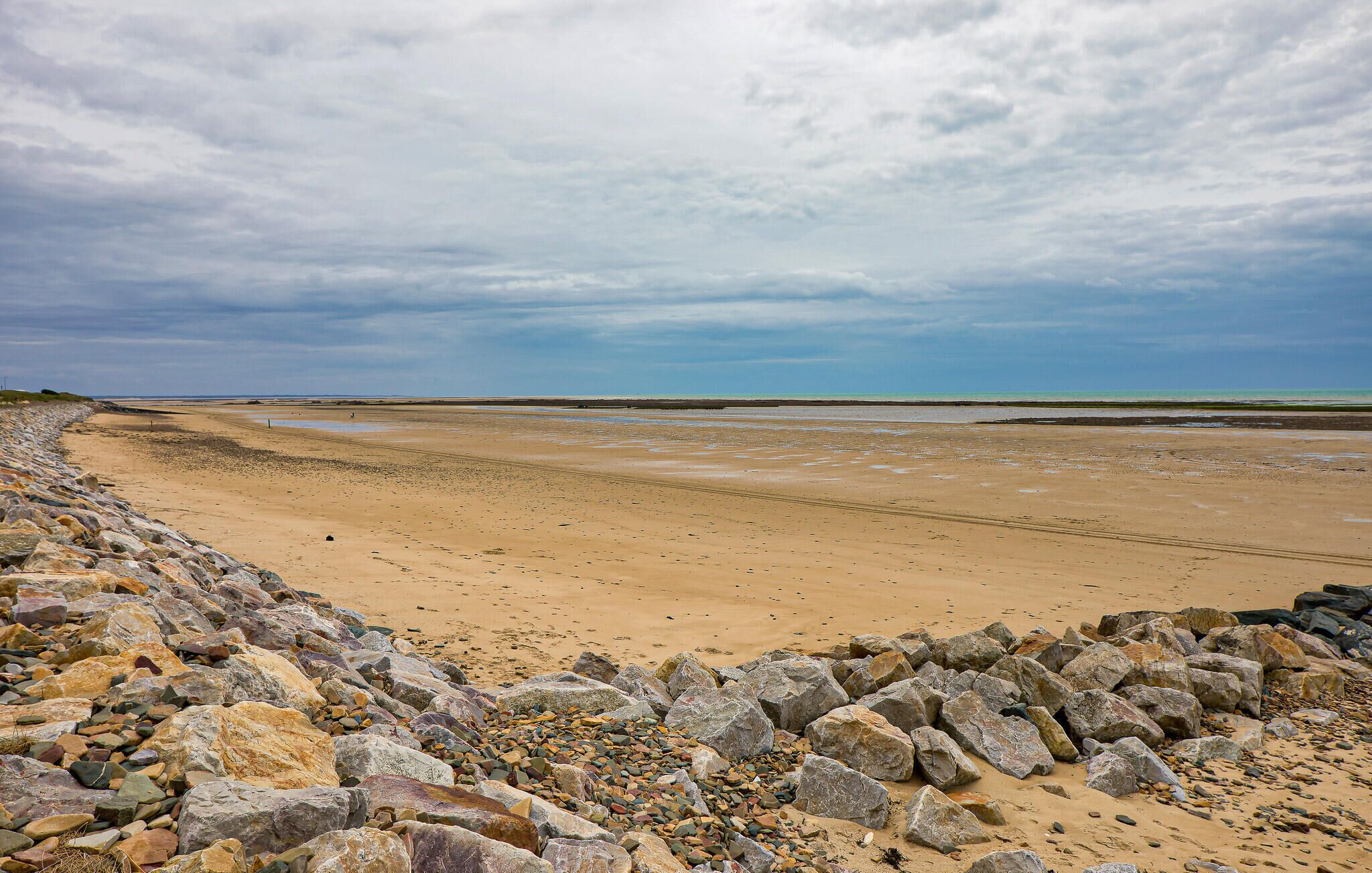 Una playa con costa rocosa y una extensa zona arenosa.
