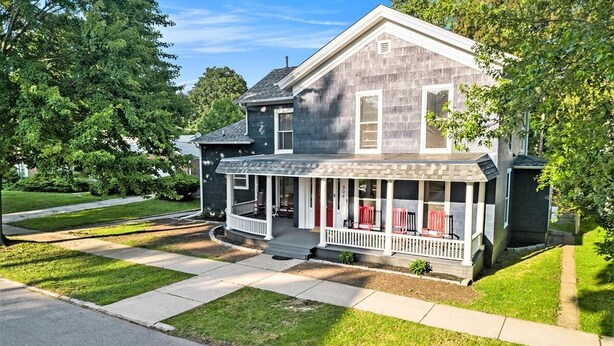 A two-story house with a porch, a covered front porch area, and a well-maintained lawn.