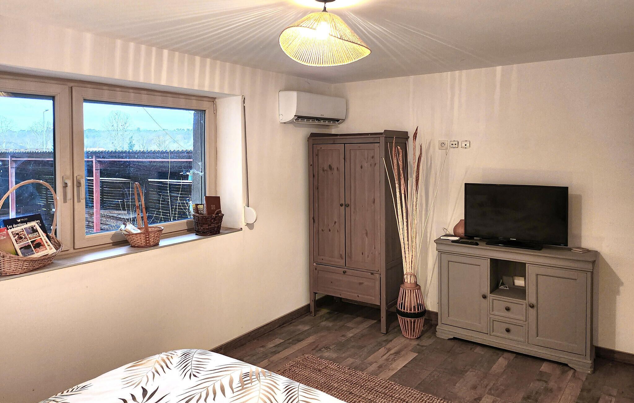 A bedroom with a large window, a wardrobe, a television, and a bed.