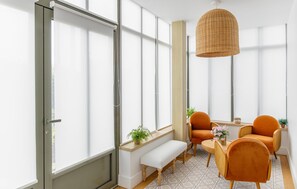 A modern room with large windows, a woven pendant light, a bench, and orange chairs. - Villa d'exception bord de mer (Noirmoutier en l'île)