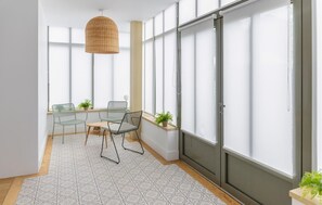 A modern room with a large window, a hanging light fixture, and a small table with chairs. - Villa d'exception bord de mer (Noirmoutier en l'île)