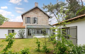 A stone house with a large glass window, a tiled roof, and a garden with various plants. - Villa d'exception bord de mer (Noirmoutier en l'île)