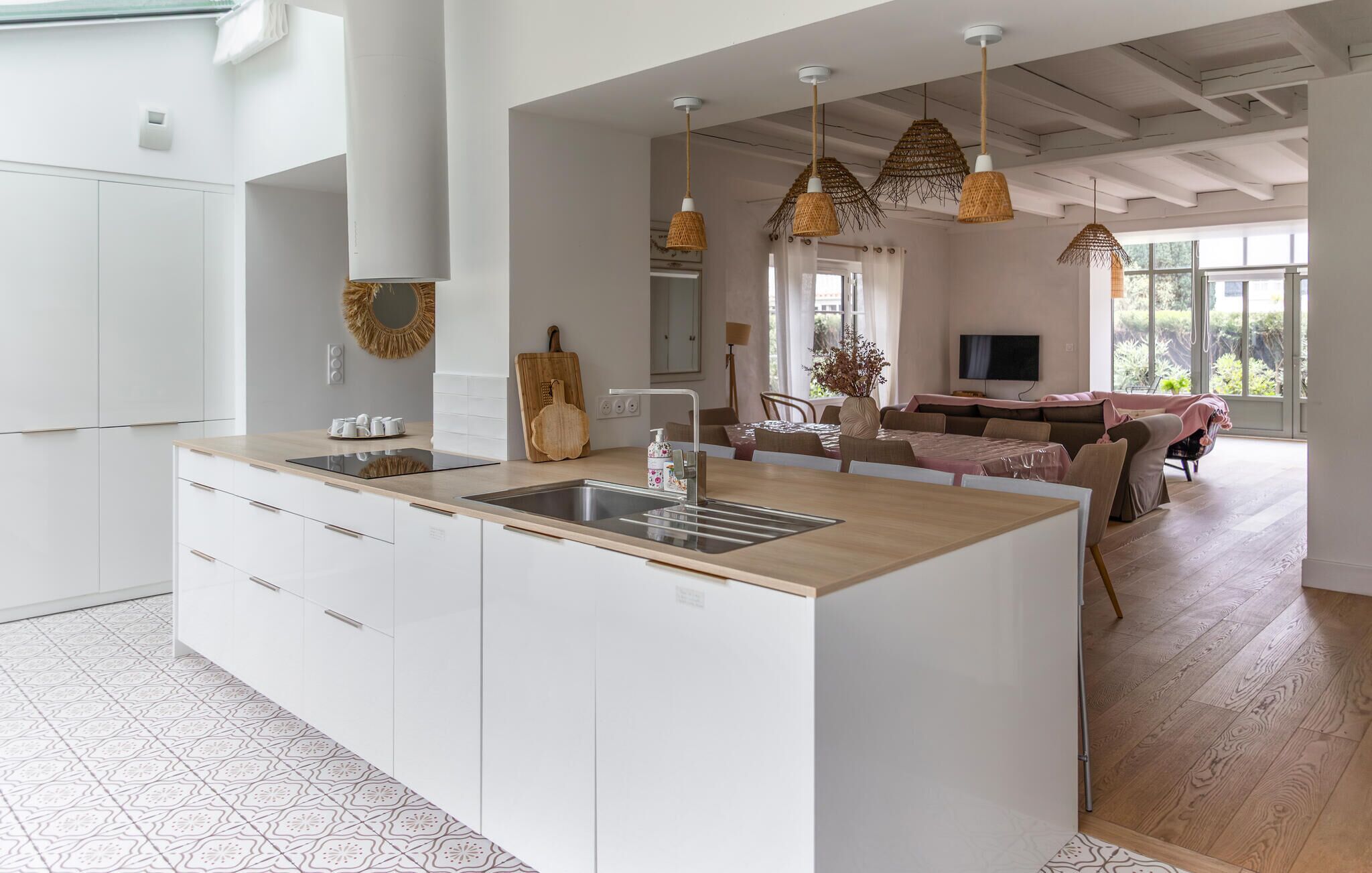 A modern kitchen with a central island, white cabinetry, and a dining area with a sofa and table.