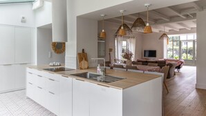 Een moderne keuken met een centraal eiland, witte kasten en een zithoek met een bank en tafel.