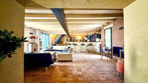 Amplia sala de estar con sofá, una mesa de centro y una silla. Una escalera conduce a un nivel superior.