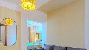 A modern living room with a sofa, a mirror, and a hanging light fixture. - Residencial Paraiso Bayahibe (Bayahíbe)