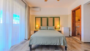 A hotel room with a bed, two bedside lamps, a ceiling fan, an air conditioning unit, and a view of the outdoors. - Residencial Paraiso Bayahibe (Bayahíbe)