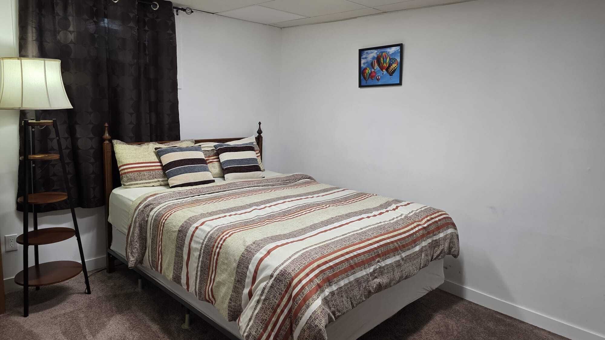 A bedroom with a bed, a bedside table, a lamp, and a painting on the wall.