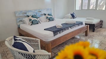 Een slaapkamer met twee bedden, een houten hoofdeinde en een witte muur.