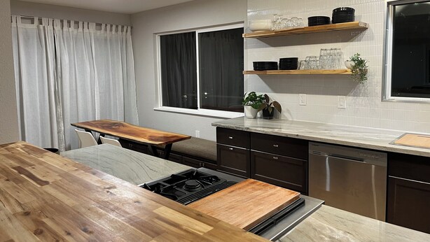 Una cocina moderna con una isla de madera, electrodomésticos de acero inoxidable y un ventanal con cortinas.
