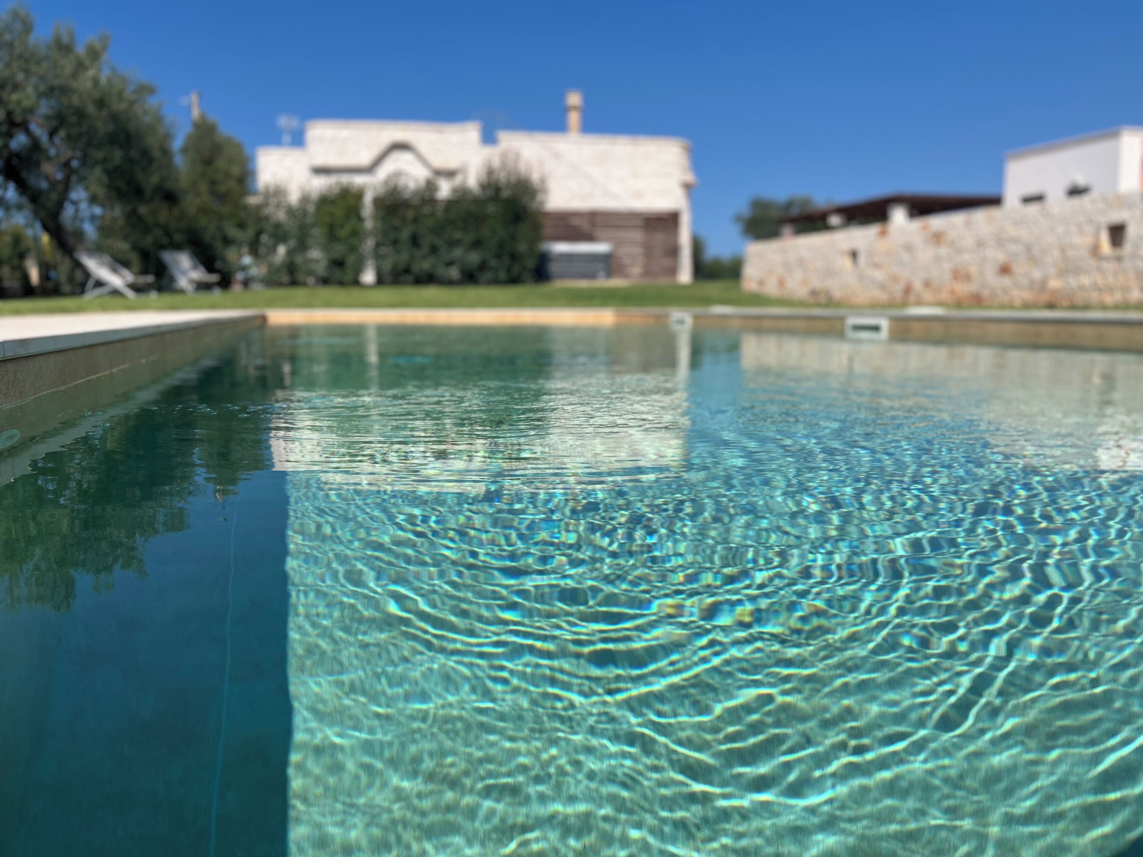 Une piscine à eau claire, dont la surface est légèrement agitée et présente de petites ondulations.