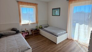 A room with two beds, a small table, a window with curtains, and a picture on the wall. - Special accommodation with its very own style, modern and lovingly furnished, (Samtens)