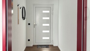 A hallway with a white door, a black coat rack, and a doormat. - Special accommodation with its very own style, modern and lovingly furnished, (Samtens)